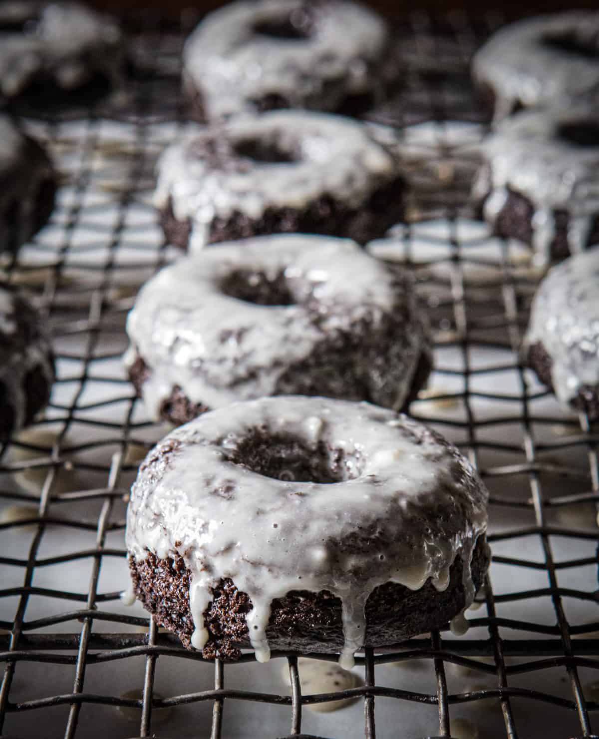 Glazed grain-free chocolate doughnuts on a cooling rack.