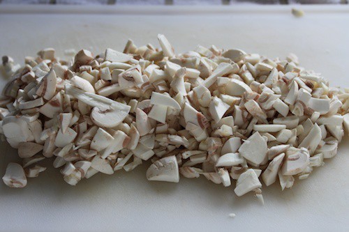 Chopped mushrooms on a white cutting board.