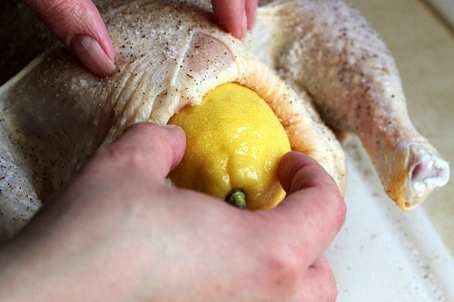 Stuffing whole lemon into raw chicken.