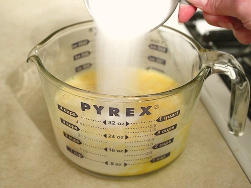 Adding sugar to the egg mixture for homemade eggnog.