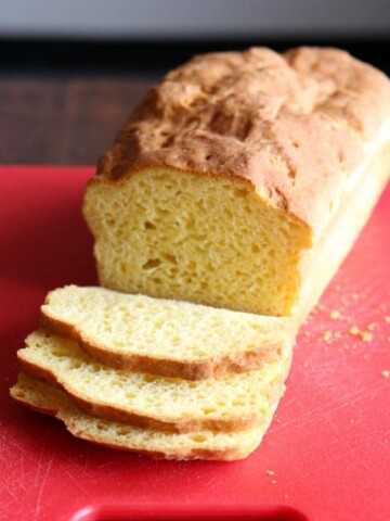 Loaf of Baked Gluten-Free Sandwich Bread on Red Cutting Board.