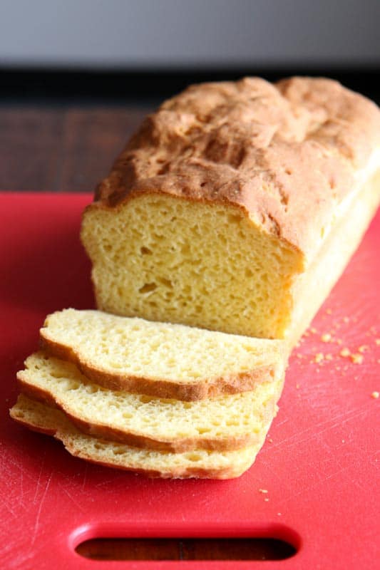 Loaf of Baked Gluten-Free Sandwich Bread on Red Cutting Board.