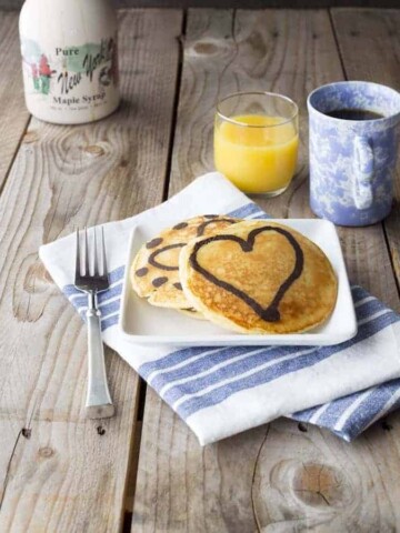 Paleo Marble Pancakes on plate. Coffee, orange juice, and a bottle of syrup sit behind the plate.