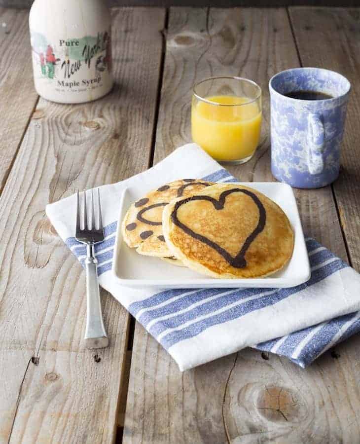 Paleo Marble Pancakes on plate. Coffee, orange juice, and a bottle of syrup sit behind the plate.