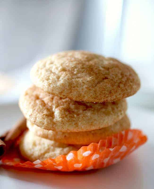 Gluten-Free Pumpkin Spice Snickerdoodles stacked on an orange cupcake liner.