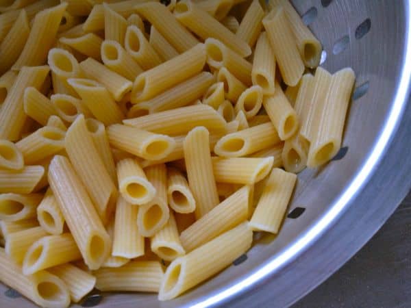 Cooked gluten-free pasta in colander.