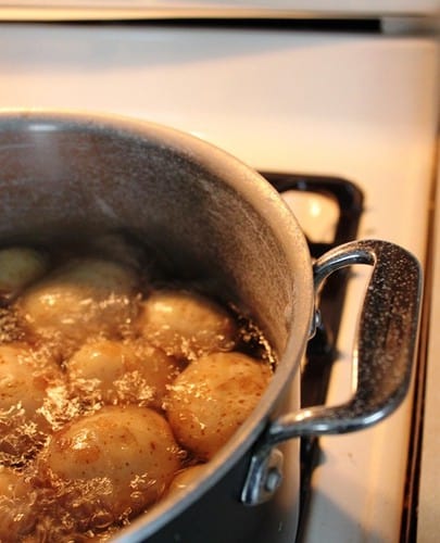 Salt potatoes boiling in a large pot.