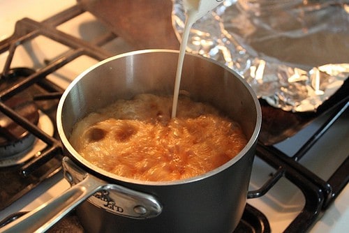 Adding cream to caramel sauce. The caramel sauce bubbles quickly.