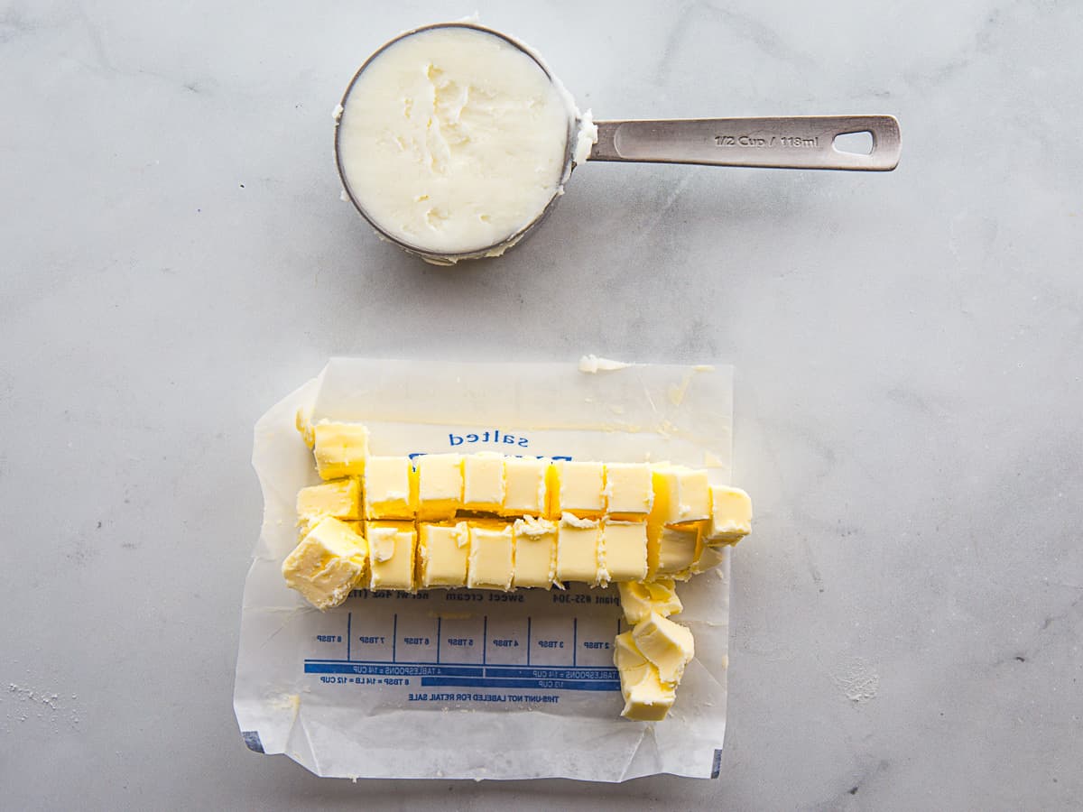 Shortening in a measuring cup. Cubbed butter on a wrapper.