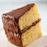 Slice of gluten-free chocolate cake with chocolate frosting on a plate.