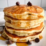 Stack of gluten-free chocolate chip pancakes drizzled with maple syrup.