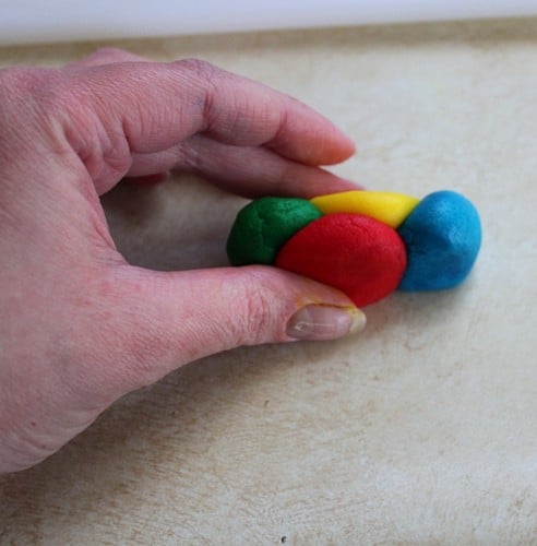 Green, yellow, blue, and red gluten-free tie dye cookie dough being pressed together.