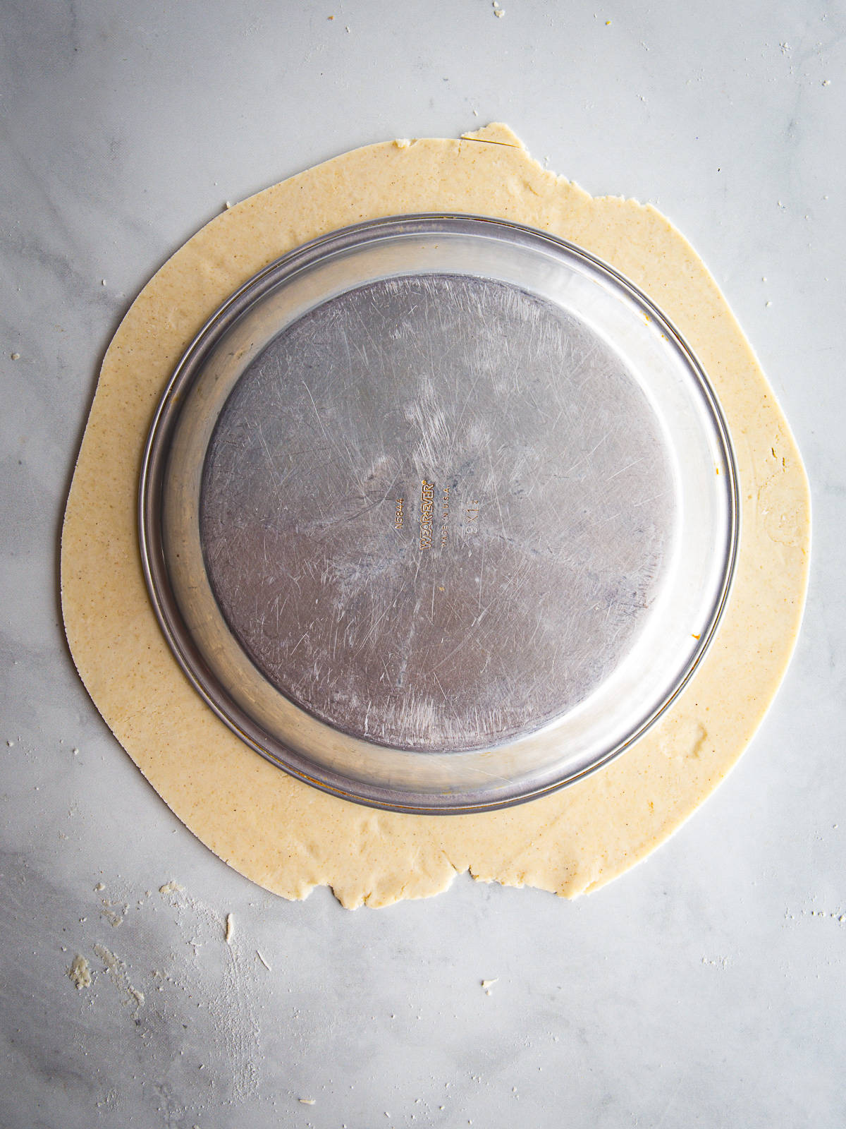 Trimmed gluten-free pie dough around an inverted pie plate.