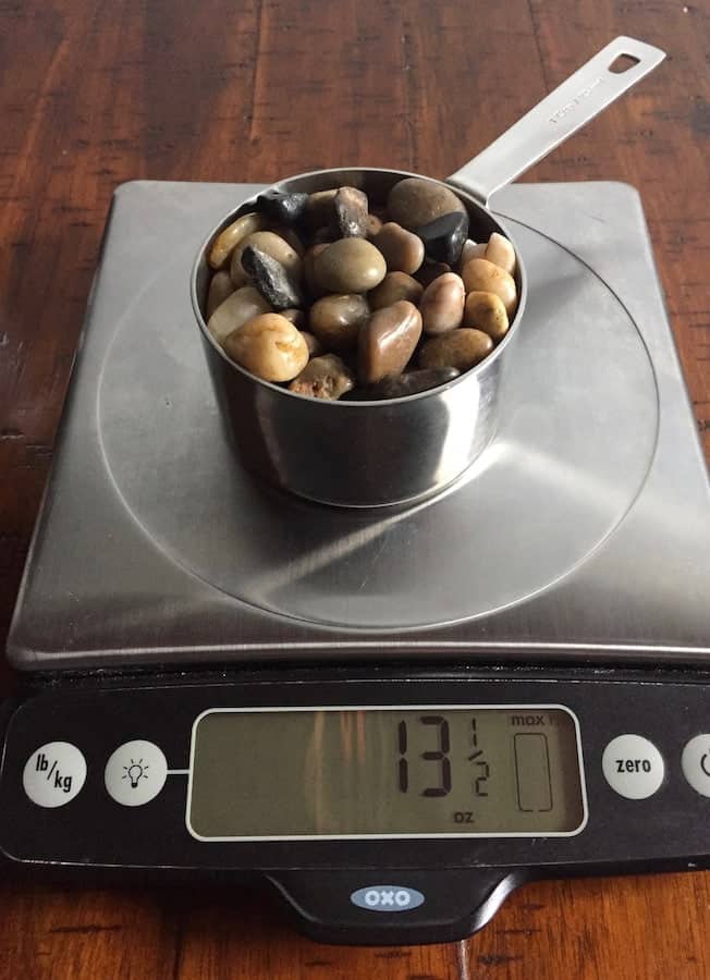 Cup on stones on a digital scale. Display reads 13 1/2 ounces.